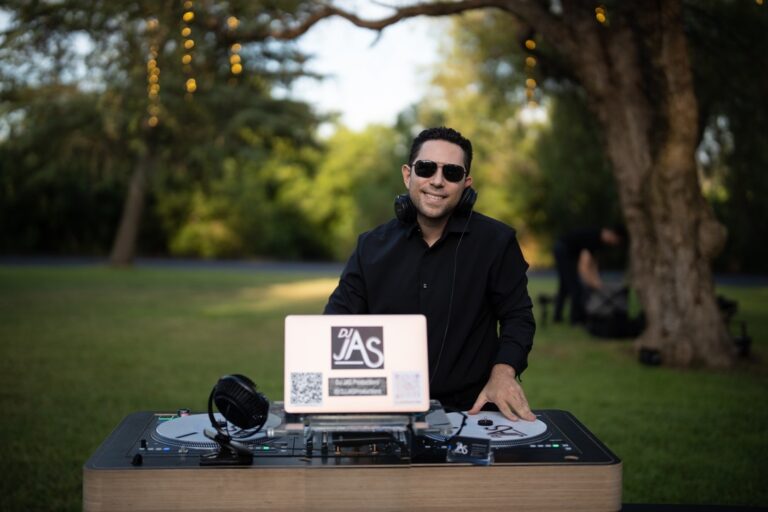 DJ JAS at his DJ booth set up on a lawn for an outdoor wedding