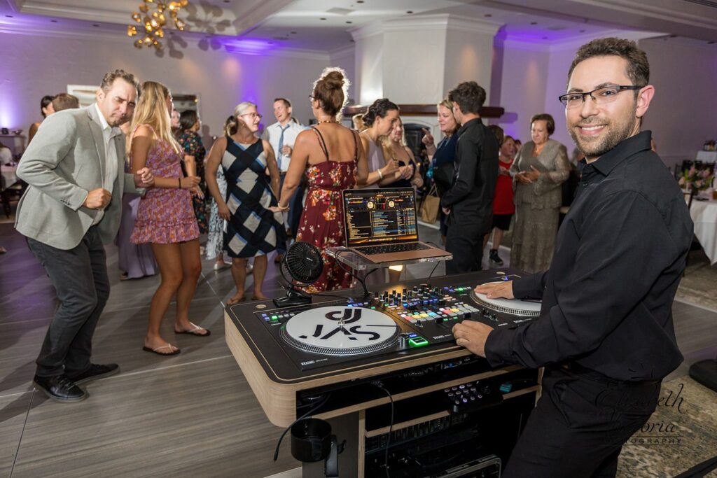 DJ JAS at his DJ booth in a hotel ballroom, ready for an event