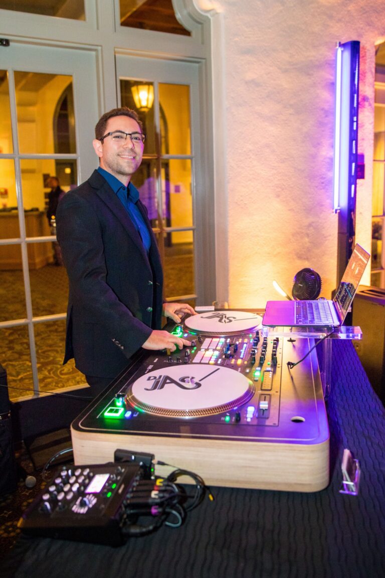 Wedding DJ JAS at his DJ booth with DJ JAS logo slipmats on the turntables and an LED light column