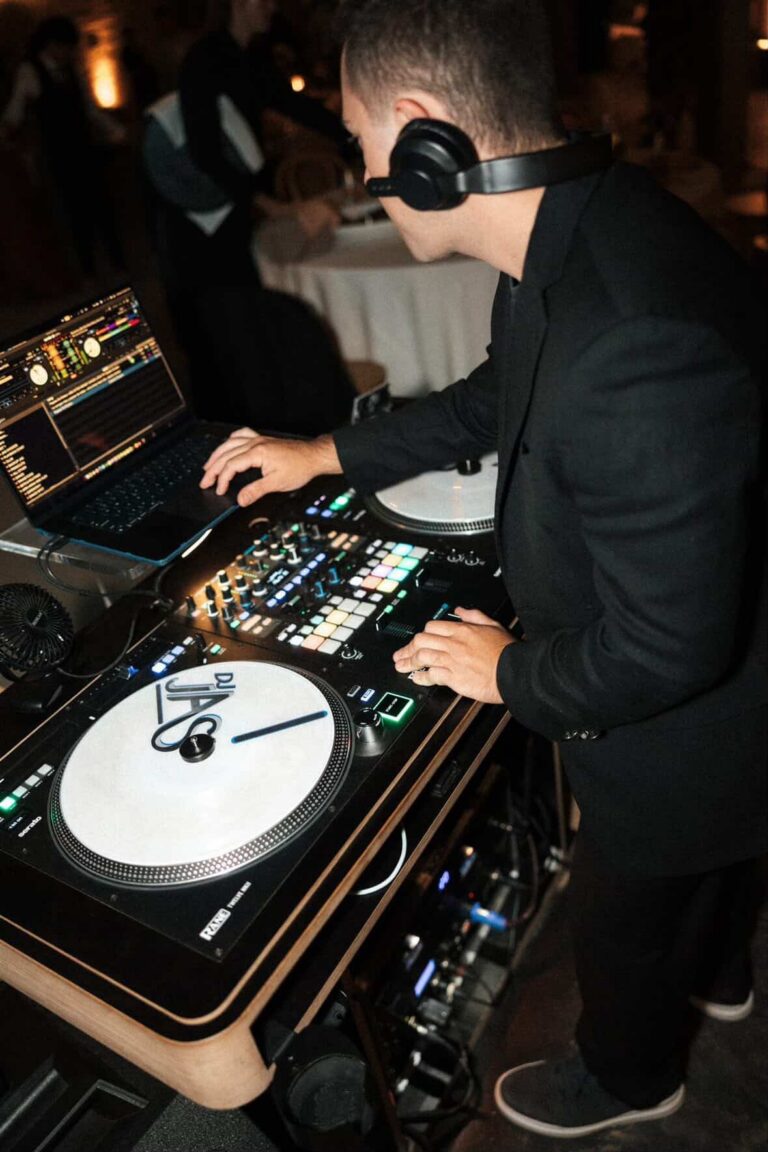 DJ JAS mixing on turntables with headphones at a wedding reception