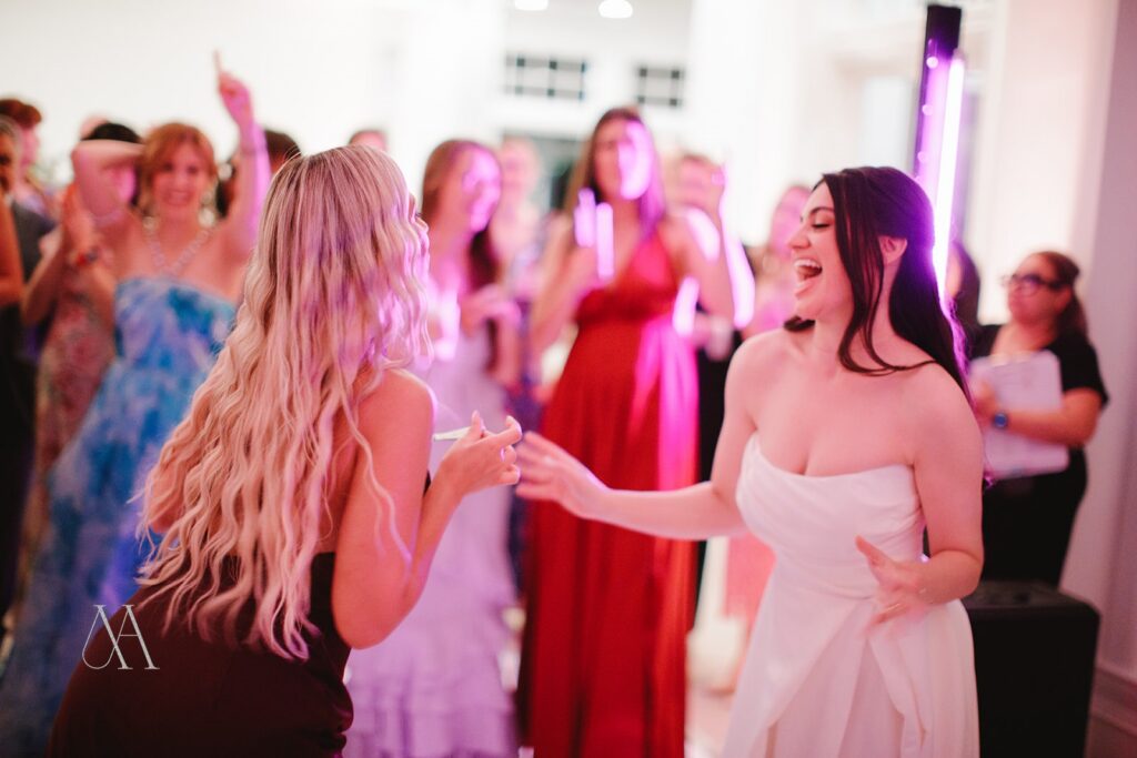 Bride dancing with a friend beside an LED light column at Sherwood Country Club