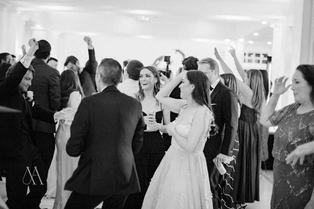 Black-and-white photo of guests dancing with hands up at Sherwood Country Club